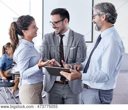 A Portrait Of A Young And Senior Smiling Businesspeople Holding A Tablet During A Meeting And Presen