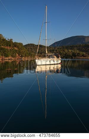 A Sailing Yacht At Anchor In A Quiet Harbor On The Coast Of The Aegean Sea.