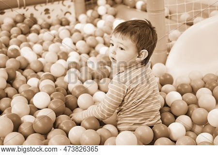 Toddler Baby Plays In The Pool With Balls. Child Boy Crawling In The Pool With Plastic Balls. Kid Ag