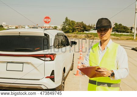 Iving Test Concept : Asian Male Officer In Charge Of Legal Driving License Exam Holding Clipboard An