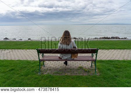 Woman Sitting On A Bench Next To Lake Balaton In Hungary Spring