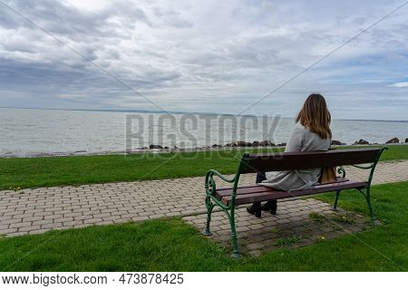 Woman Sitting On A Bench Next To Lake Balaton In Hungary Spring