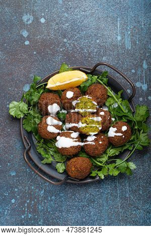Plate Of Fried Falafel Balls Served With Fresh Green Cilantro And Lemon Top View On Rustic Concrete 