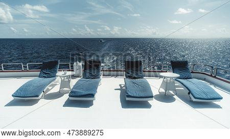 Scene In The Maldives Features A Luxurious Yacht On Calm Waters, With Blue Cushioned Loungers On Its