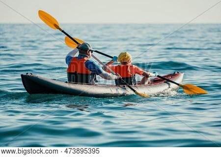 Happy Couple Kayaks In An Inflatable Kayak On The Sea At Sunset. Couple Kanoeing In The Sea Near The