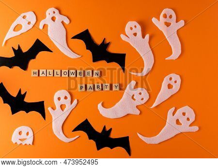 White Ghosts And Bat Craft For Halloween Party. Wrapping Paper Ghost On Orange Background Top View. 