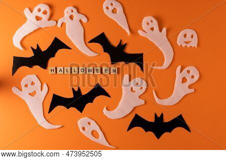 White Ghosts And Bat Craft For Halloween Party. Wrapping Paper Ghost On Orange Background Top View. 