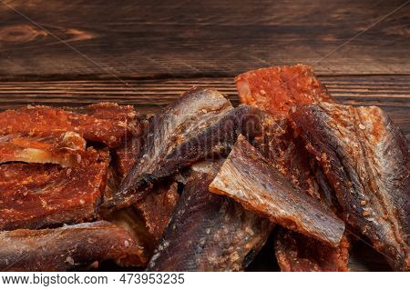 Pieces Of Cleaned Dried Fish On Wooden Background. Dry Peppered Pollack. Amber With Pepper.