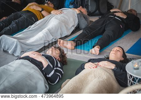 Vilnius, Lithuania - March 26 2023: Group Of Young People During A Yoga Class Lying On A Mat, Breath
