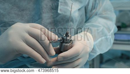 The Surgeon Changes The Nozzle On A Surgical Drill During An Operation On A Broken Bone. The Surgeon