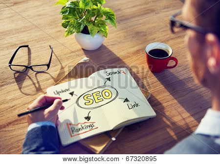Hipster Writing SEO Concepts on his Note
