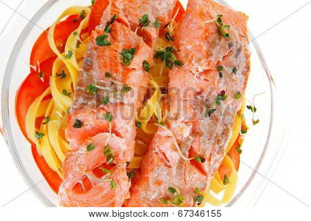 fresh fried natural pink salmon on italian traditional tagliatelle backed with tomato and vegetables isolated over white background