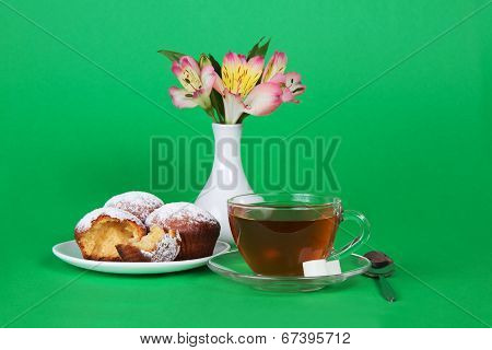 Appetizing cupcakes, tea, flowers in vase