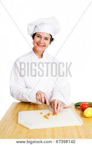 Pretty female chef chopping up vegetables in her kitchen.  Isolated on white.  