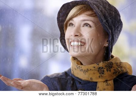 Surprised young woman in rain, smiling and looking up.