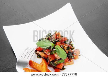 vegetable salad : cherry tomatoes and basil with sweet baked potato served on white plate with sauceboat full blask soy sauce on wood