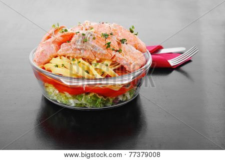 fresh fried natural pink salmon on italian traditional tagliatelle backed with tomato and vegetables served over black wooden table