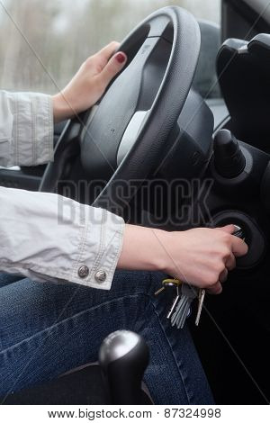 Women driver hand inserting car key and starting engine. 