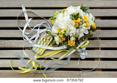 wedding photo set in yellow and gray colours: rings, telephone case and bouquet of roses, Craspedia, Hydrangea, Brunia silver flowers