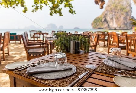 leisure, travel and tourism concept - close up of table setting at open-air restaurant on beach