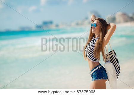 Portrait of happy sexy girls with beach bag posing against the sea.