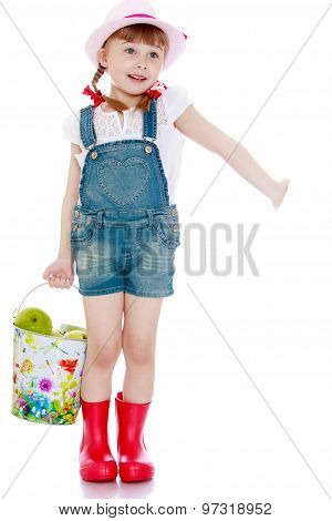 Beautiful little girl with a bucket of apples