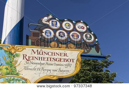 MUNICH, GERMANY - JUNE 04, 2015: Maypole at Viktualienmarkt with a colored figure and the signs of the Munich beers