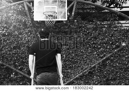 Man Standing With Broken Leg In Plaster Cast Using Crutches At Basketball Court