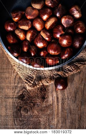 Heap of edible fresh chestnuts on old wooden table. Group of ripe big chestnuts with copy space macro