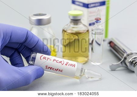 Scientist with blue latex gloves holds vials of ZIKA virus in laboratory for analysis