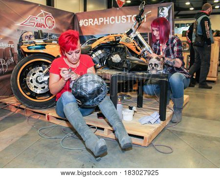 St. Petersburg Russia - 15 April, Drawing of airbrushing on a helmet,15 April, 2017.
International Motor Show IMIS-2017 in Expoforurum.
Visitors and participants of the annual moto-salon in St. Petersburg.