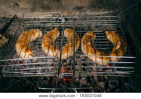 Sausages on the grill with flames. Sausages on the coals.