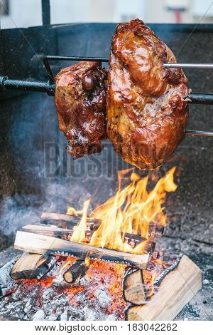 Large chunks of delicious pork hams cooked on an open fire. The street food. Food outdoors. Camping and cooking on a spit over the fire. Camping.