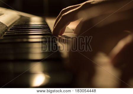 Close-up soft focused atmospheric photography of a hand playing the piano keys. Concept: Music creating, composing, lyrics, performance