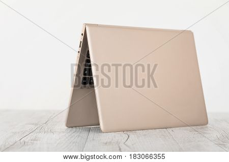 Ultra-thin notebook. The gold notebook on the desk the open notebook lies on a wooden background.