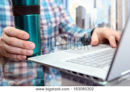 Business man working and analyzing financial figures on a graphs using laptop. Cup of tee or cofee near.