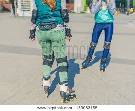 Two girls rollers meet each other in the park. Meeting of friends for roller skating.