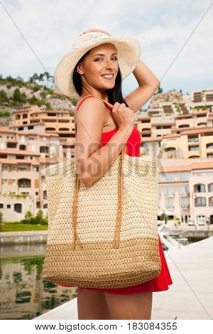 wman walks a city on the beach on hot summer day un beautiful red dress with hat