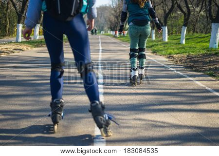 Competitions in roller skating.Two girls on roller skates ride along the road. The second girl is tired and stopping.