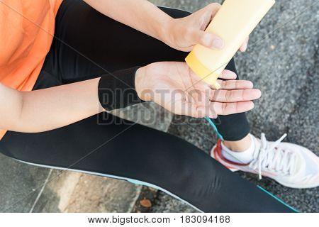 Young Asian Female Runner Sitting Down Putting Lotion On Hand And Arm