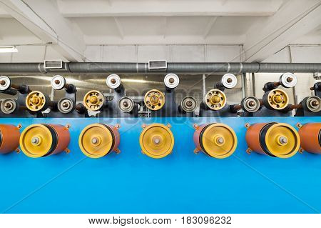 Rotating rubberized wheels of the winding machine. A lot of rotating wheels are yellow.