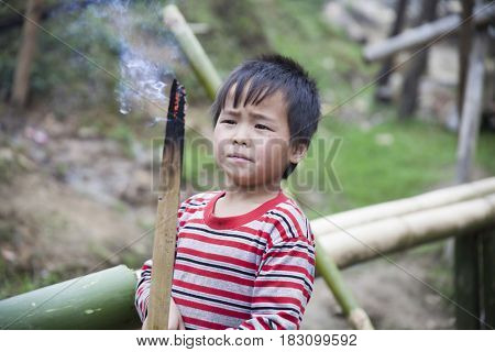 Sa Pa, Vietnam - 12 March, 2017: Ethnic minority, Hmong boy playing with the fire in tradition village of Cat cat, Sapa, Vietnam