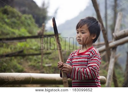 Sa Pa, Vietnam - 12 March, 2017: Ethnic minority, Hmong boy playing with the fire in tradition village of Cat cat, Sapa, Vietnam