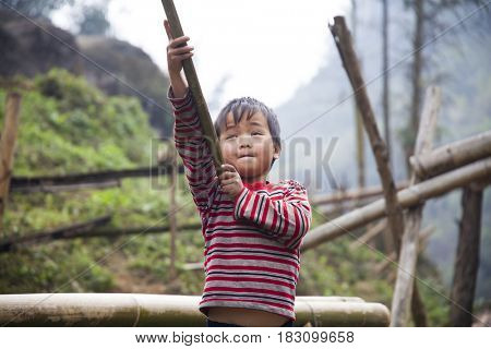 Sa Pa, Vietnam - 12 March, 2017: Ethnic minority, Hmong boy playing with the fire in tradition village of Cat cat, Sapa, Vietnam