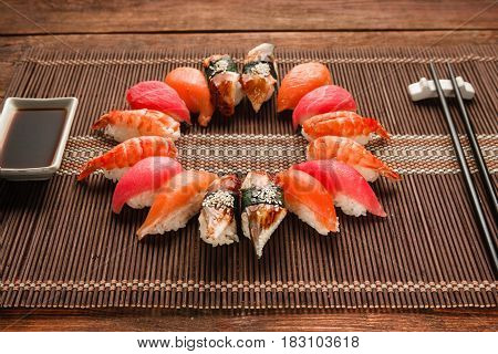 Colorful japanese sushi set, seafood. Great assortment of nigiri nigiri served like circle on brown straw mat, close up. National seafood, restaurant menu photo.