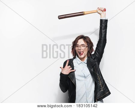 Young beautiful girl in black leather coat holding batt and gesturing while smiling at camera.