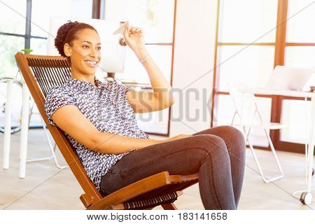 Young woman in office holding paper plane