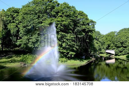 Fountain with a rainbow in Riga river canal that flows through Bastion park (Bastejkalns). Riga, capital of Latvia.