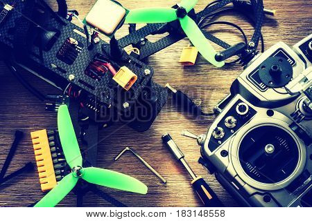 Drone quadcopter with a flight controller over wooden background. Top view flat lay