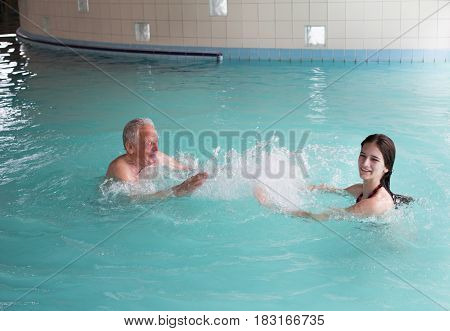 Grandfather and granddaughter having fun in indoor swimming pool